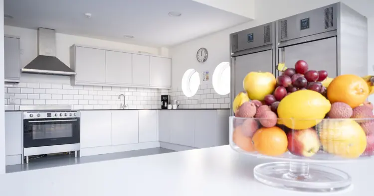 Clean bright fitted kitchen with bowl of fruit in foreground